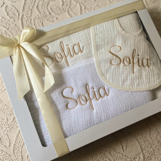 
Coffret naissance bébé en gaze de coton comprenant couverture, trousse de toilette et bavoir personnalisés au prénom, cadeau doux et pratique.