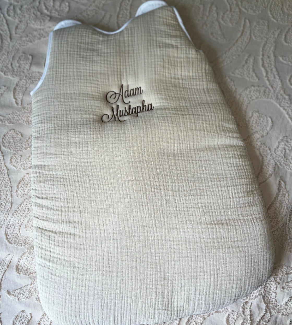 Gigoteuse bébé 0-6 mois en tissu doux, personnalisée avec le prénom brodé, couleur neutre, idéale pour offrir confort et sécurité au nouveau-né.
