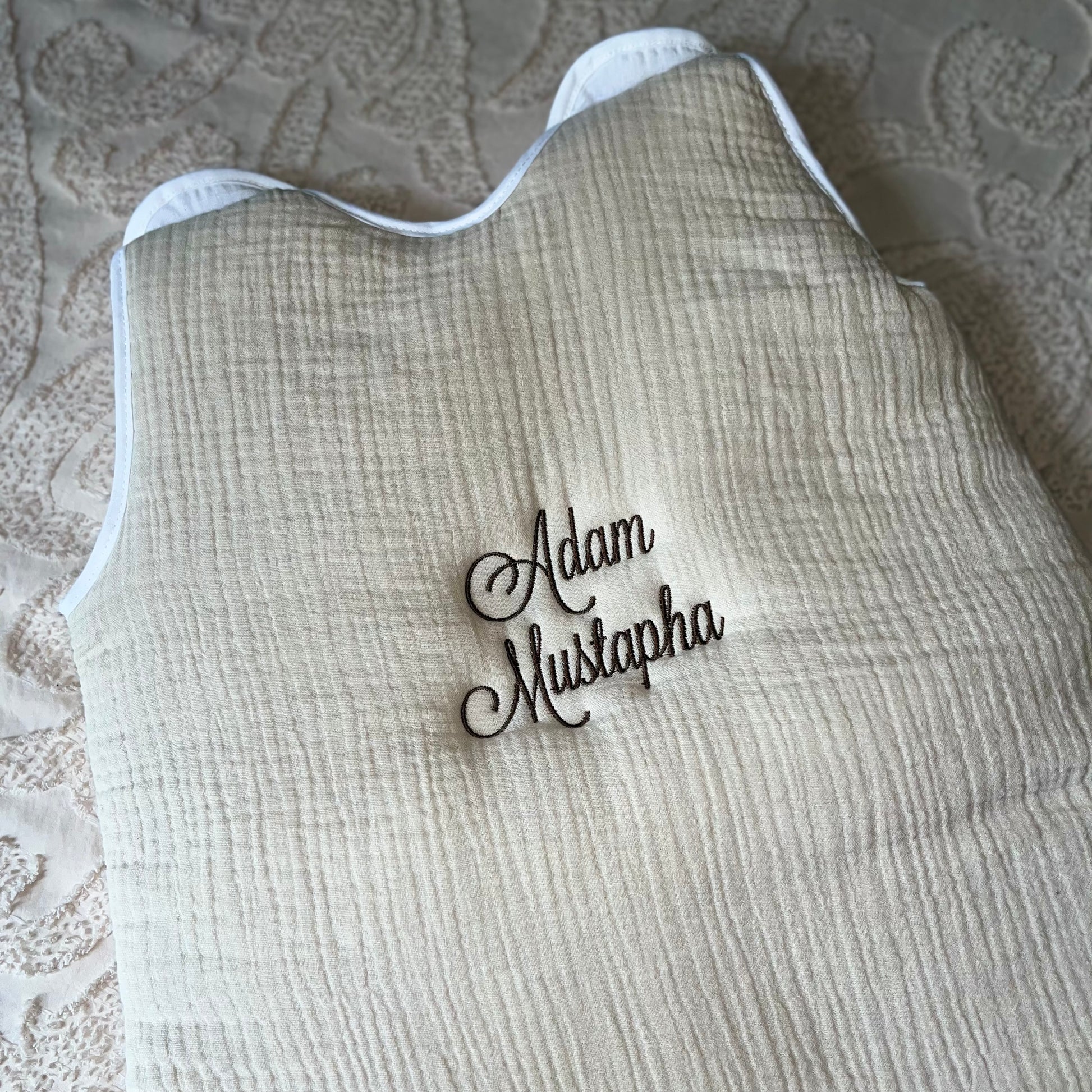 Gigoteuse bébé 0-6 mois en tissu doux, personnalisée avec le prénom brodé, couleur neutre, idéale pour offrir confort et sécurité au nouveau-né.